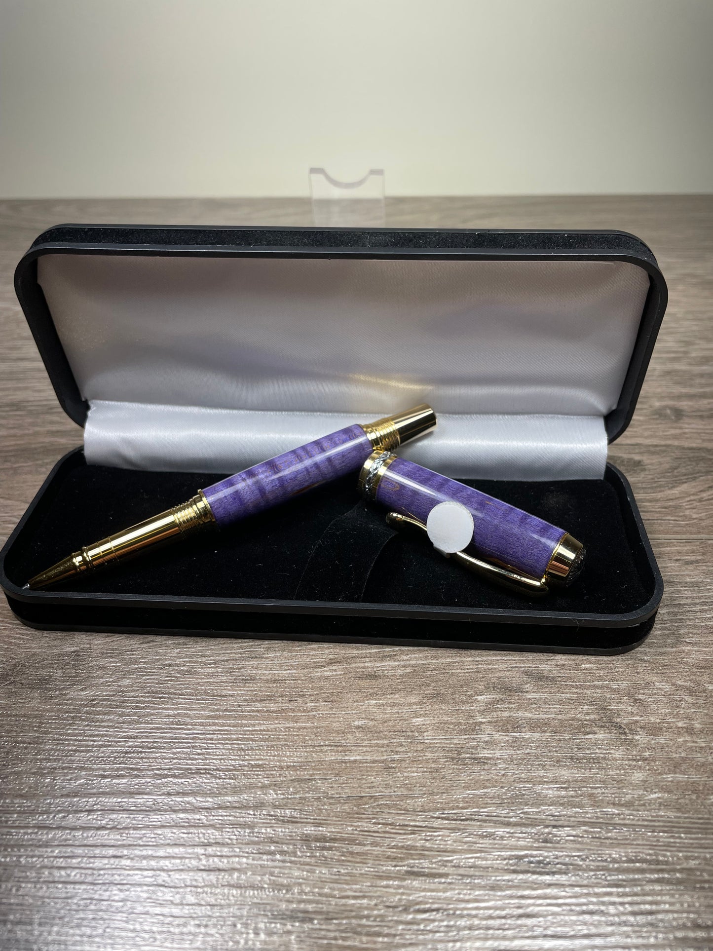 Purple pen with gold accents in a black case on a wooden surface